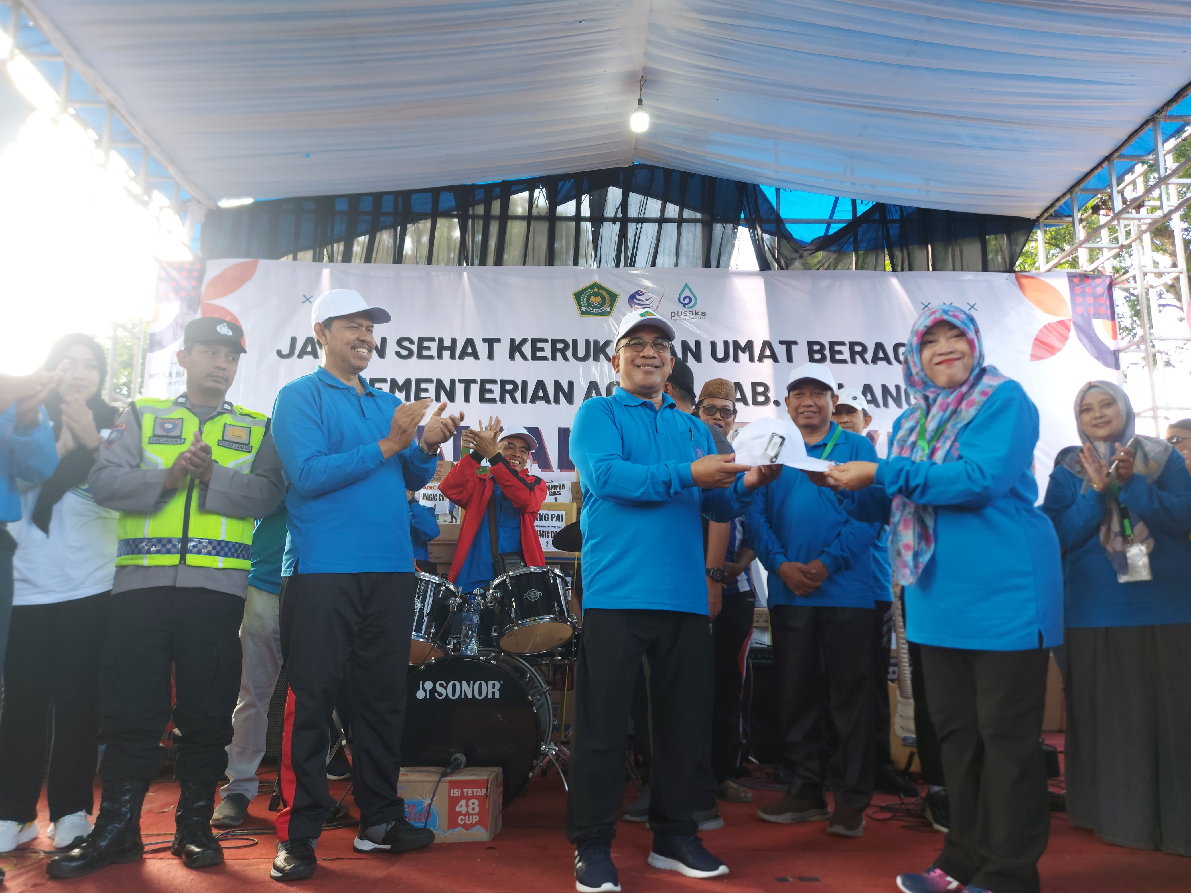 Simbolis: Kepala MTsN 3 Malang Dra Hj Warsi MPd menyerahkan topi secara simbolis kepada Kepala Kemenag Kabupaten Malang Drs H Sahid MM dalam acara Jalan Sehat Hari Amal Bhakti ke-79 di Lawang.