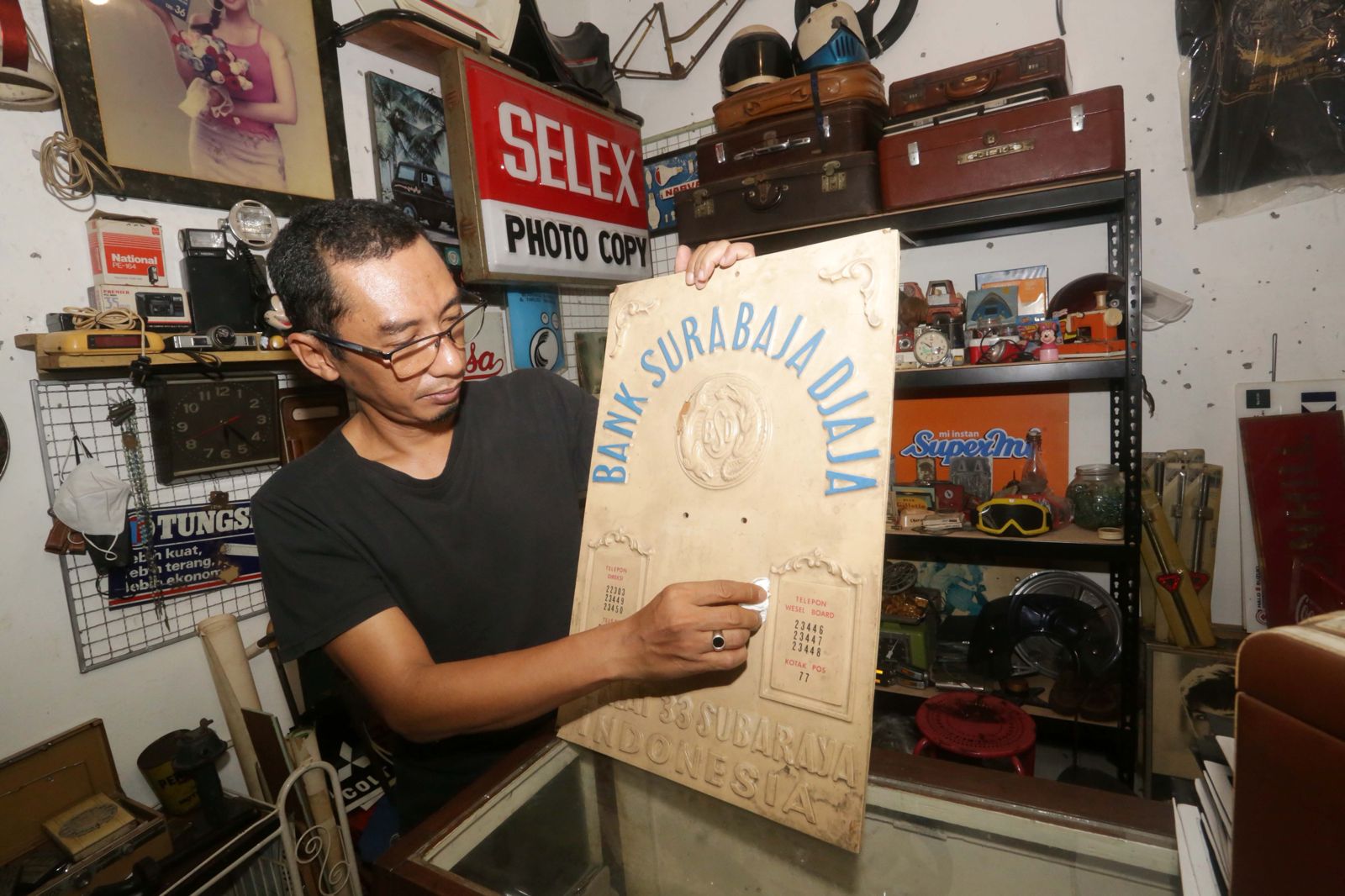 TETAP BERTAHAN: Salah satu pedagang Pasar Nostalgia Bratang membersihkan koleksi barang antik kemarin siang. ROBERTUS RIZKY/ JAWA POS