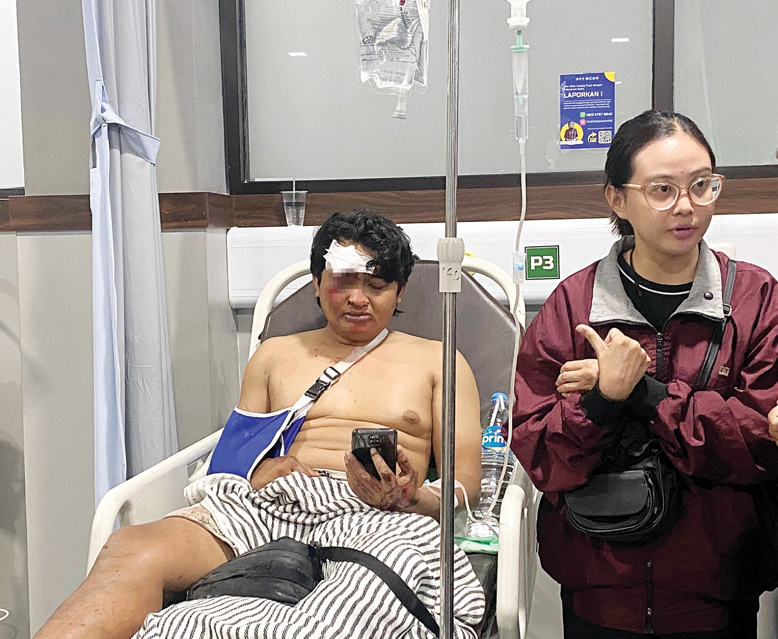 DALAM PERAWATAN: Muhammad Syafiudin Nuris Wanto terisak ketika melihat foto almarhum istrinya di HP, Rabu malam (8/1). Syafiudin harus menjalani perawatan akibat dislokasi di bahu kanannya.