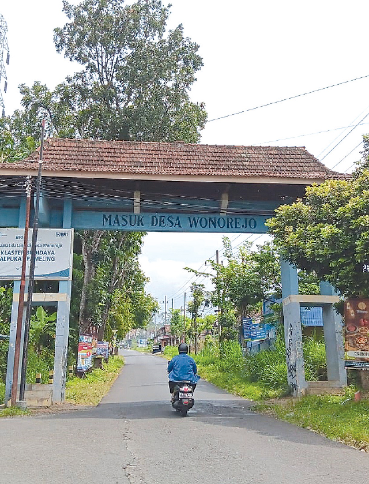 PRODUK UNGGULAN: Seorang pengendara melintasi gerbang Desa Wonorejo, Kecamatan Lawang yang menjadi sentra alpukat pameling, kemarin (12/1). INDAH MEI YUNITA