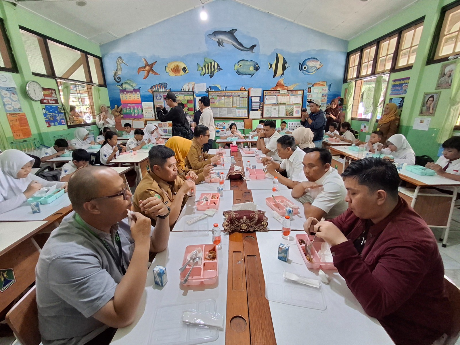 HARI PERTAMA: Jajaran forkopimda, mitra makan bergizi gratis (MBG), dan pelajar menikmati hidangan bersama di ruang kelas 6 SDN Lowokwaru 3, kemarin. NABILA AMELIA / RADAR MALANG