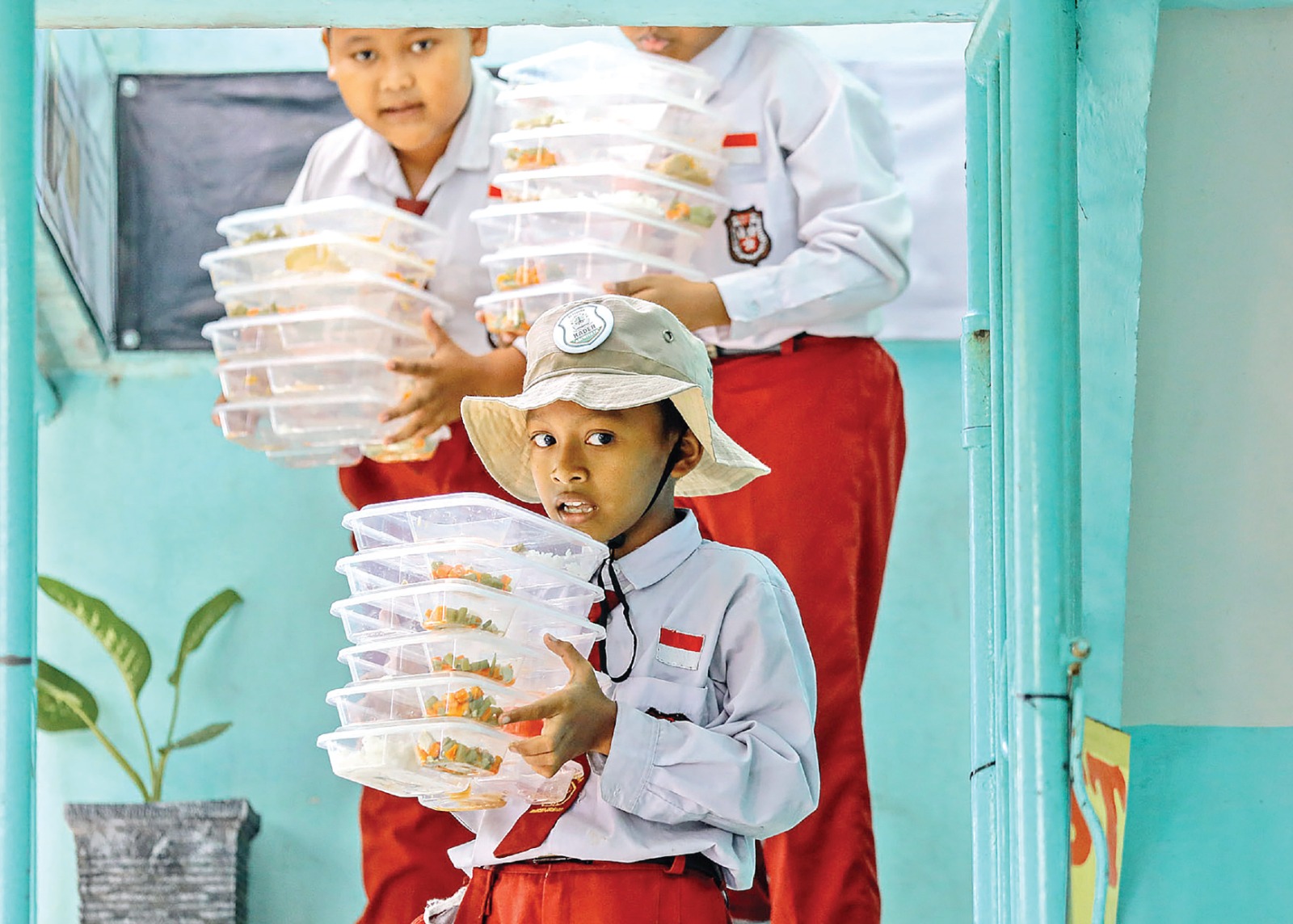 MASIH ADA SISA: Siswa SD di Surabaya mengangkut tempat makan setelah selesai digunakan untuk MBG kemarin siang. DIPTA WAHYU/JAWA POS