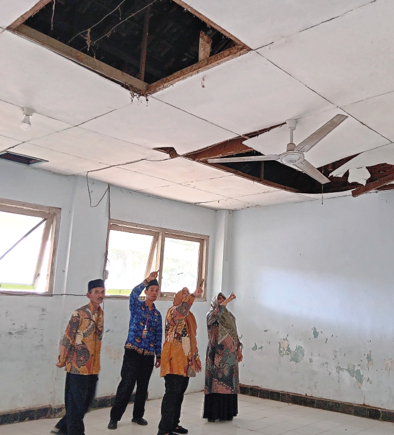 TAK LAYAK: Beberapa guru SDN 1 Kidangbang, Kecamatan Wajak menunjukkan plafon ruang kelas yang ambrol beberapa waktu lalu. Hingga kini belum ada perbaikan dari Pemkab Malang. INDAH MEI YUNITA