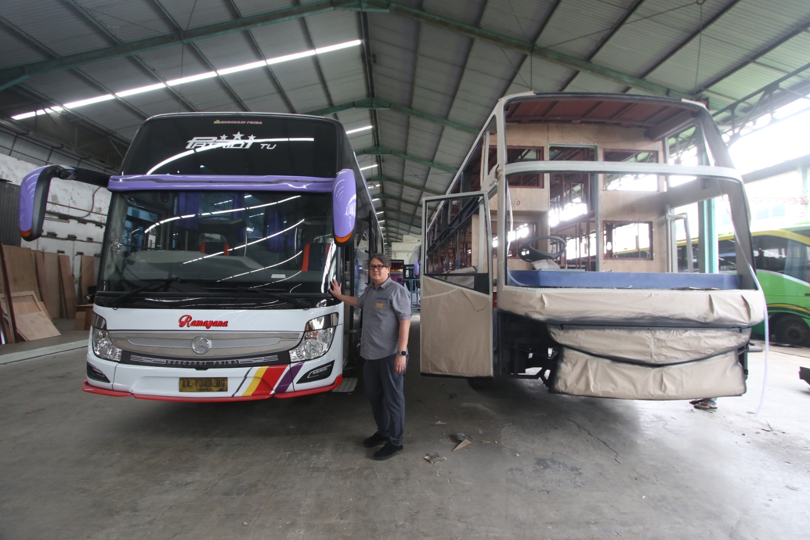 GENERASI KEDUA: Direktur Morodadi Prima David Lie berdiri di antara bus yang sudah jadi dan yang masih dalam proses produksi. (SATRIA CAHYONO/RADAR MALANG)