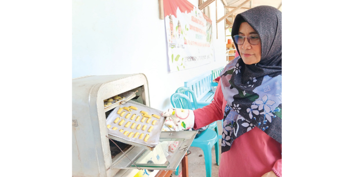 MAKANAN TAMBAHAN: Salah satu anggota PKK Desa Ternyang, Kecamatan Sumberpucung, Srianingsih memanggang kue berbahan tepung ikan lele. (INDAH MEI YUNITA/RADAR KANJURUHAN)