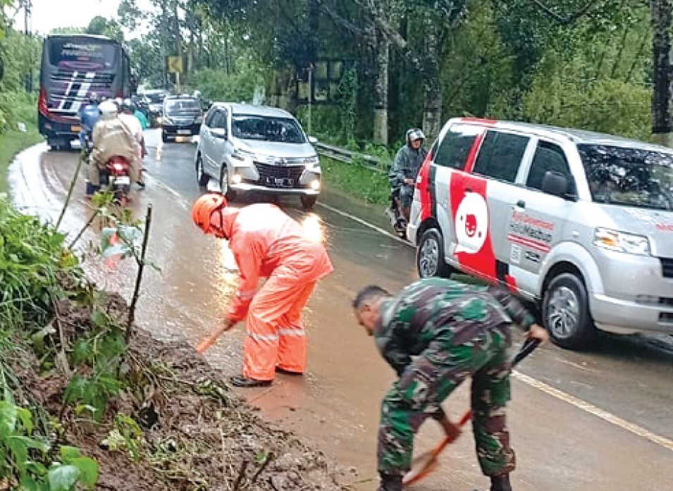 HAMBAT LALU LINTAS: Tim dari TNI, Polri, dan BPBD Kabupaten Malang membersihkan material longsor yang menutupi ruas jalan Malang-Kediri kemarin. BPBD KABUPATEN MALANG FOR RADAR KANJURUHAN