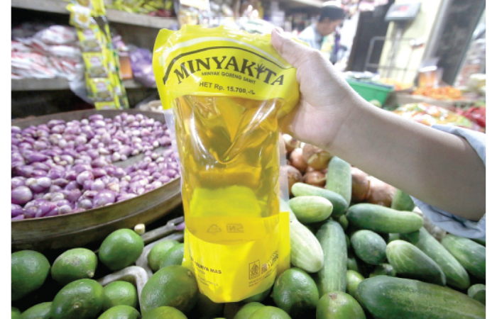 BANYAK TANGAN: Salah satu pedagang menunjukkan Minyakita kemasan satu liter, kemarin. (SATRIA CAHYONO / RADAR MALANG)
