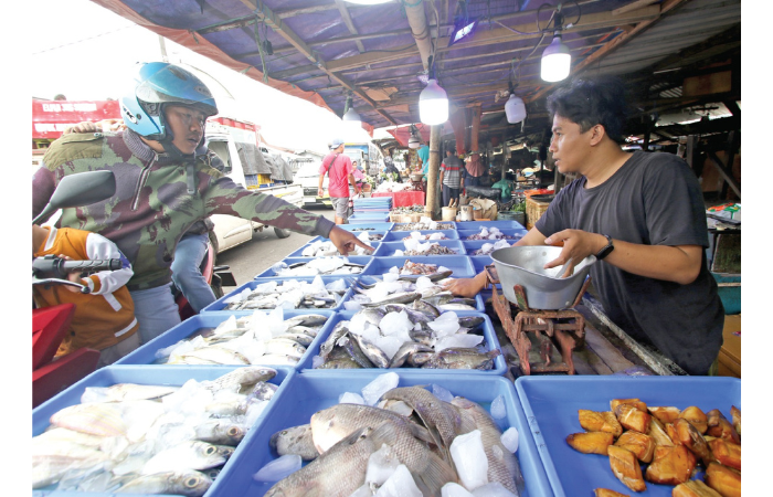 TIDAK TERIMBAS: Salah satu warga memilih ikan di Pasar Gadang, kemarin. Meski cuaca belum menentu, banderol beberapa komoditas tetap stabil. (SATRIA CAHYONO / RADAR MALANG)