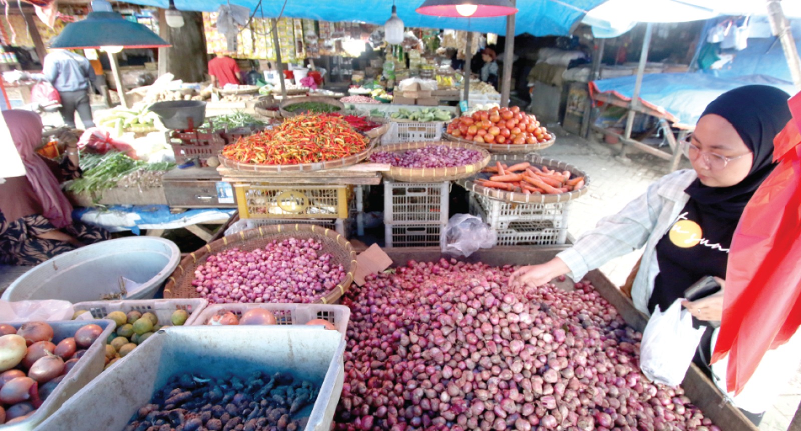 BAHAN POKOK: Salah satu pembeli memilih bawang merah yang dijual di Pasar Gadang kemarin. (SATRIA CAHYONO/RADAR MALANG)