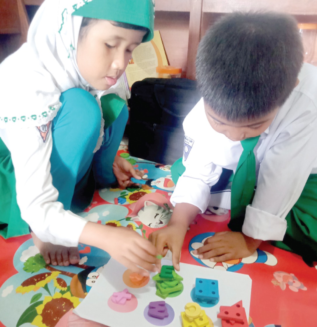 KONSISTEN: Dua siswa MI Sunan Giri berkerja sama menata kepingan puzzle sesuai warna. (MI SUNAN GIRI JABUNG FOR RADAR MALANG)