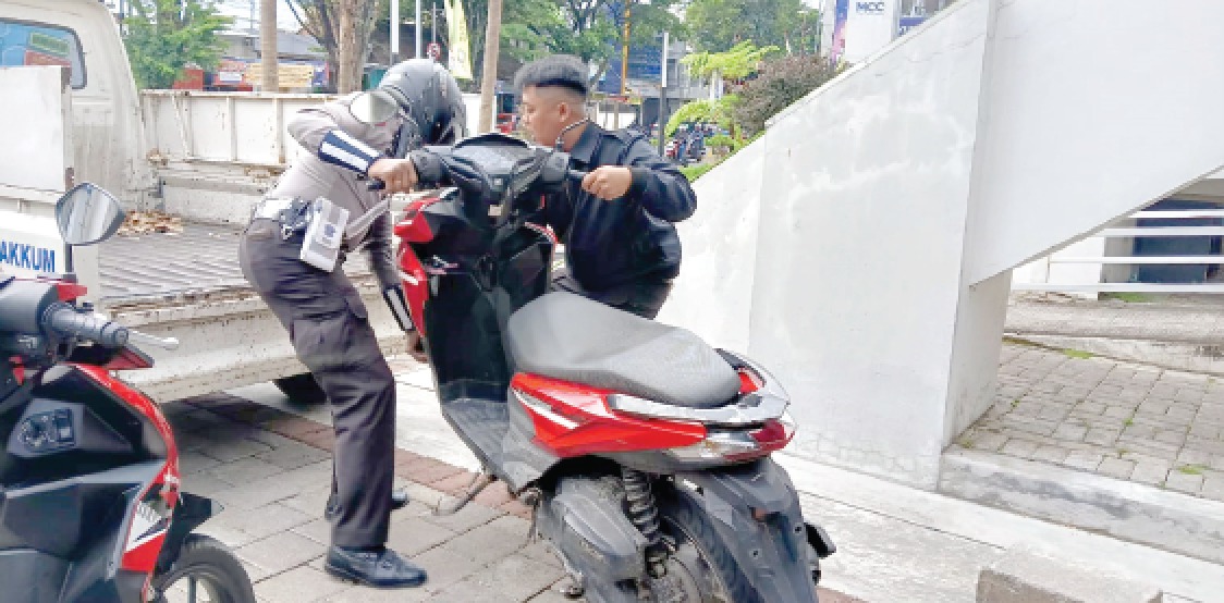 BUKTI: Personel Satlantas Polresta Malang Kota mengangkut motor yang pengendaranya kedapatan melakukan pelanggaran, kemarin. (AKHMAD RIYADH / RADAR MALANG)