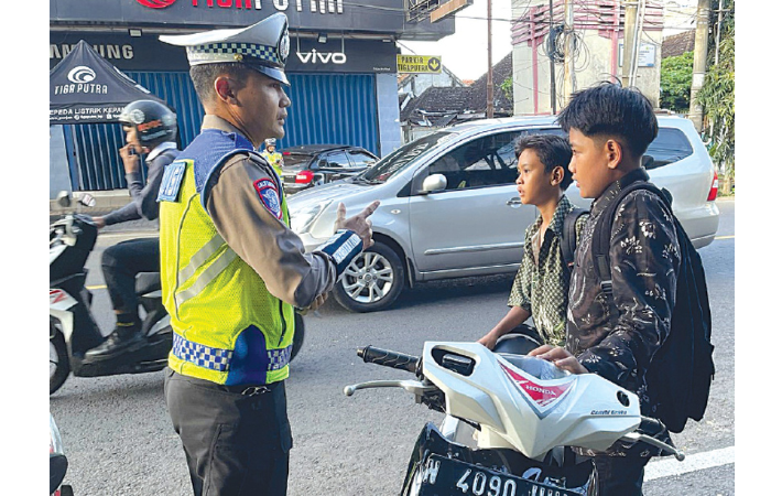MELANGGAR: Anggota Satlantas Polres Malang memberhentikan pengen dara tak memakai helm di Jalan Sultan Agung, Kepanjen kemarin (13/2). (SATLANTAS POLRES MALANG FOR RADAR KANJURUHAN)