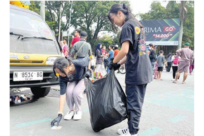 PEDULI LINGKUNGAN: Siswa SMPK Kosayu 2 mengangkut sampah di kawasan CFD Ijen (16/2). (FARAL DIVA FOR RADAR MALANG)