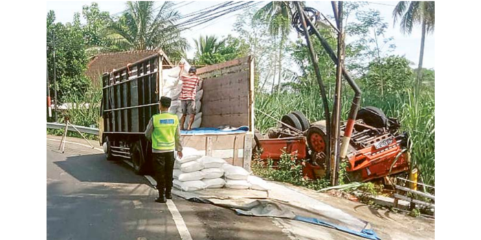 EVAKUASI: Truk pengangkut beras terbalik di tikungan Jalan Raya Sukorame, Desa Bumirejo, Kecamatan Dampit kemarin (18/2). Beras yang berserakan terpaksa dipindah ke truk lain.