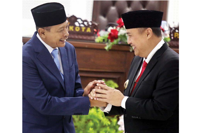 LANJUTKAN PROGRAM: Wali Kota Malang terpilih Wahyu hidayat (kiri) berjabat tangan dengan Pj Wali Kota Malang Iwan Kurniawan setelah sidang paripurna 10 Februari lalu. (SATRIA CAHYONO/ RADAR MALANG)