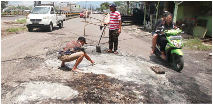 DILANJUTKAN PEMKOT: Dua warga mengecor lubang di Jalan Rajasa, Kelurahan Bumiayu, Kecamatan Kedungkandang, kemarin. Mereka mengumpulkan material secara swadaya.