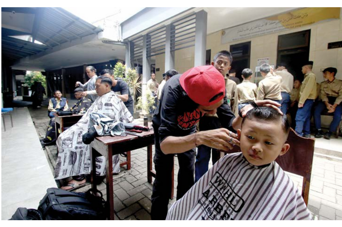 Anggota Gerakan Barber untuk Rakyat (GBUR) mencukur rambut salah satu anak di Pondok Pesantren Muhammadiyah Al Munawaroh, Kecamatan Kedungkandang, kemarin. (SATRIA CAHYONO / RADAR MALANG)
