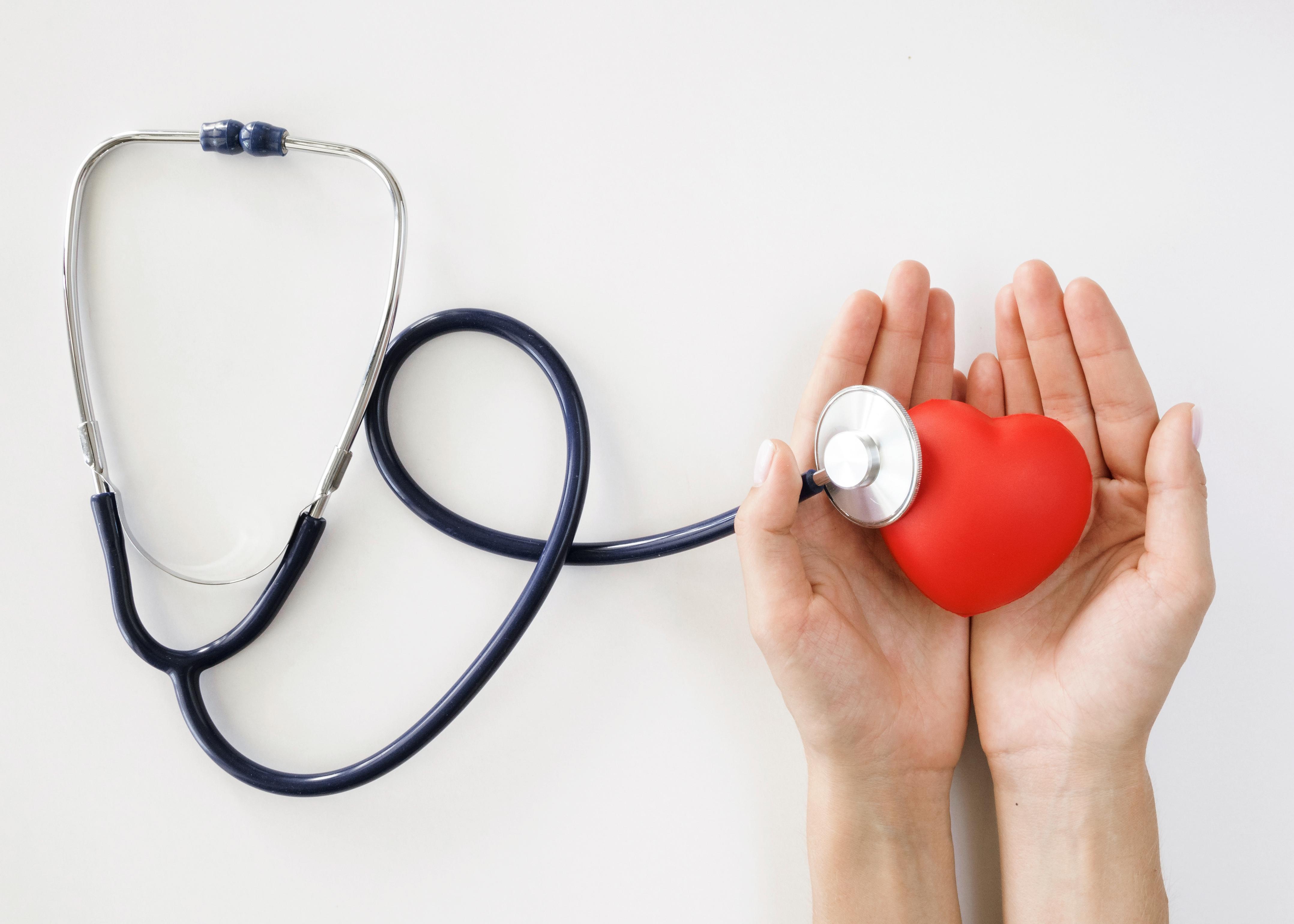 Flat lay of hands holding heart shape with stethoscope (Freepik)
