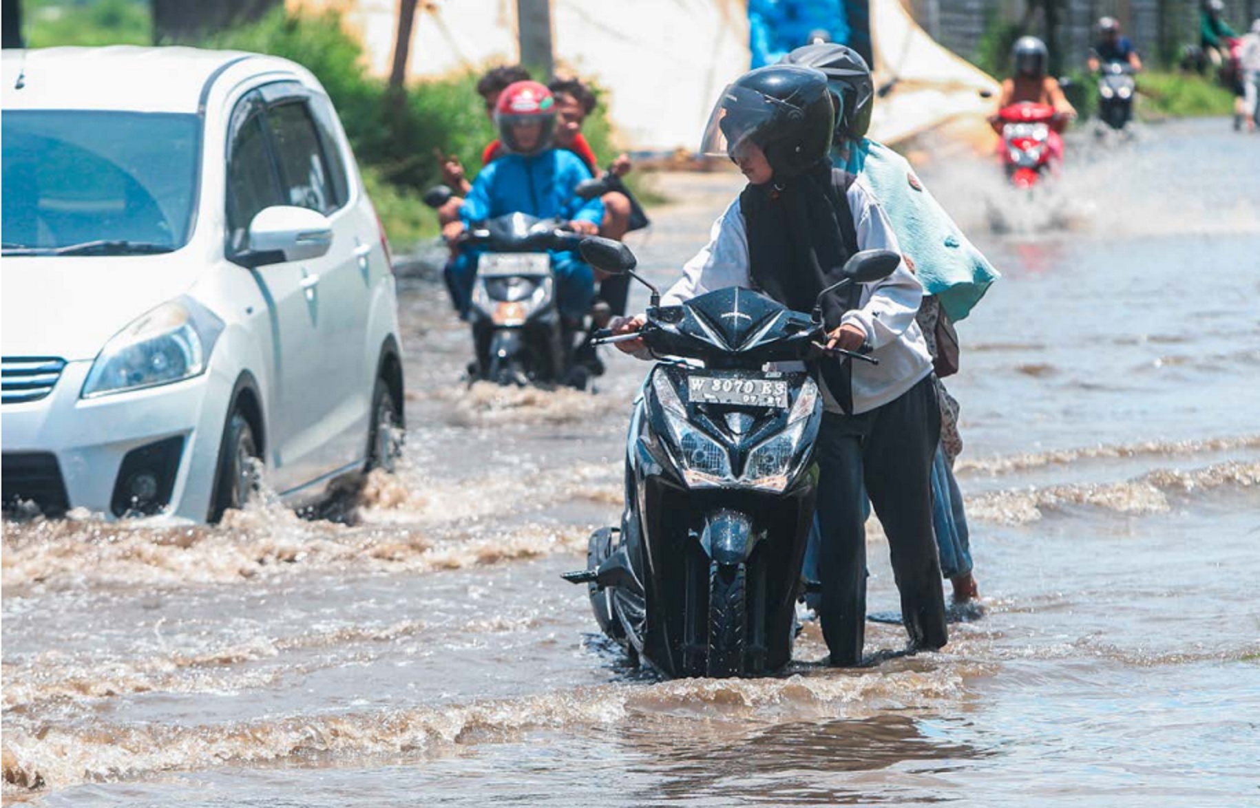 KENA BANJIR: Seorang pengendara sepeda motor mendorong kendaraannya yang mogok di area menuju Stadion GBT kemarin.