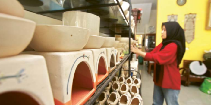 BERKURANG: Salah satu pegawai di toko souvenir keramik di Kelurahan Dinoyo merapikan dagangannya (SATRIA CAHYONO / RADAR MALANG).