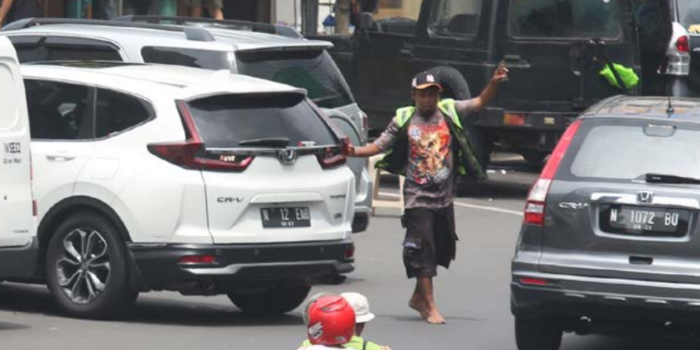 MELEK TEKNOLOGI: Salah satu juru parkir di koridor Kajoetangan Heritage bersiap menyeberangkan salah satu pengendara, kemarin (SATRIA CAHYONO / RADAR MALANG).