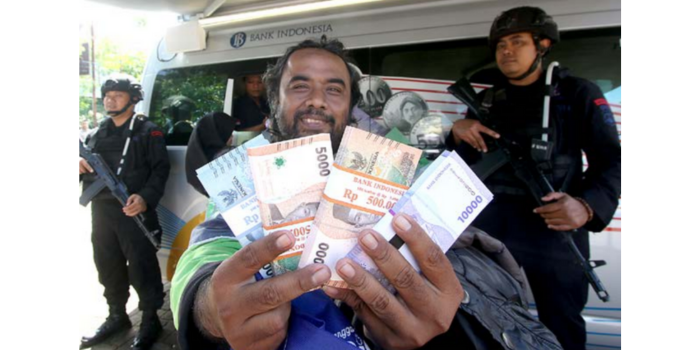 TUKAR DUIT: Salah seorang warga menunjukkan uang baru yang didapat dari Mobil Kas Keliling Bank Indonesia (BI) Malang di halaman kantor Kelurahan Merjosari (SATRIA CAHYONO/RADAR MALANG).