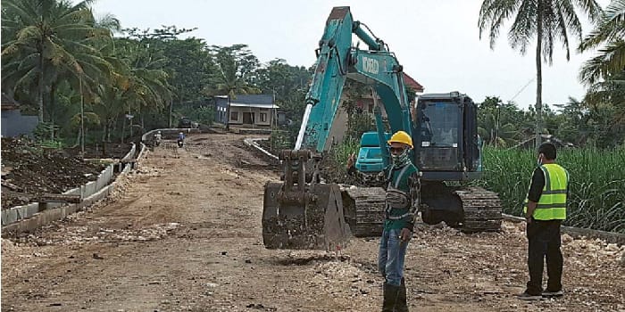 AKSES WISATAWAN: Satu unit alat berat diterjunkan untuk melebarkan drainase di jalur Gondanglegi-Bantur kemarin (12/3).