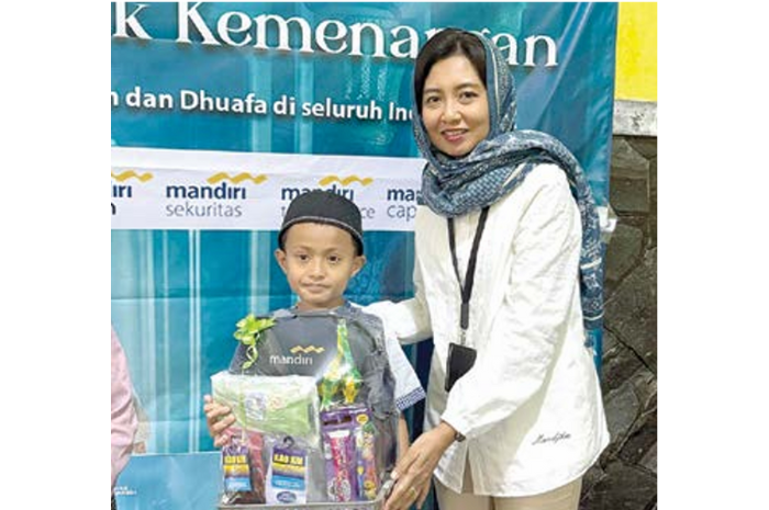BERBAGI: Vice President Bank Mandiri Area Malang Lucia Ike Purwandini menyerahkan santunan kepada anak yatim. (DUROTUL KARIMAH/RADAR MALANG)