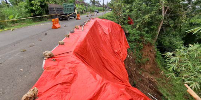 BUTUH PERBAIKAN: Terpal warna oranye menutup ruas jalan di Desa Tunjungsari, Kecamatan Bantur yang tergerus longsor.