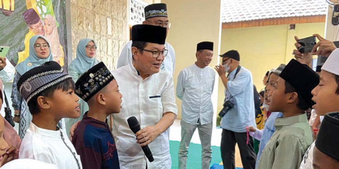 MENYANYI: Komisaris PT ACA Iwan Kurniawan mengajak anak yatim Endraw untuk memandu anak yatim lainnya bersama-sama menyanyikan lagu Indonesia Raya (Mardi Sampurno/Radar Malang).
