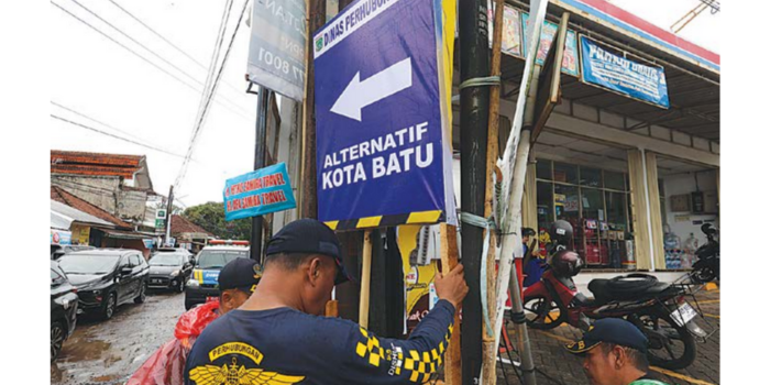 Tim dari Dinas Perhubungan (Dishub) Kabupaten Malang memasang rambu jalur alternatif di Desa Kepuharjo, Kecamatan Karangploso kemarin (19/3) (Darmono/Radar Malang).