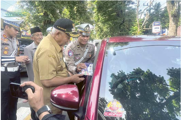 SOSIALISASI: Bupati Malang H M. Sanusi dan Kasatlantas Polres Malang AKP Widyagana membagikan stiker mudik untuk pengendara kemarin (20/3). (POLRES MALANG FOR RADAR KANJURUHAN)