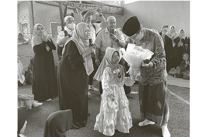 Salah satu perwakilan anak yatim Aqila menyerahkan buket kepada Iwan Kurniawan yang berulang tahun di arena lapangan futsal Tri Abina, Kecamatan Wonosari kemarin (20/3). (MARDI SAMPURNO/RADAR MALANG)
