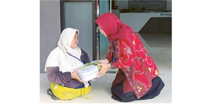 MOMENT HARU: Kepala Cabdindik Wilayah Kabupaten Malang Dr Dra Ema Sumiarti MSi (kanan) memberikan parsel kebaran kepada loper Ifa. ()