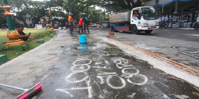 SISI LAIN DEMO: Para pekerja membersihkan joging track yang mengelilingi Alun-Alun Tugu dari coretancoretan yang dibuat para demonstran kemarin.