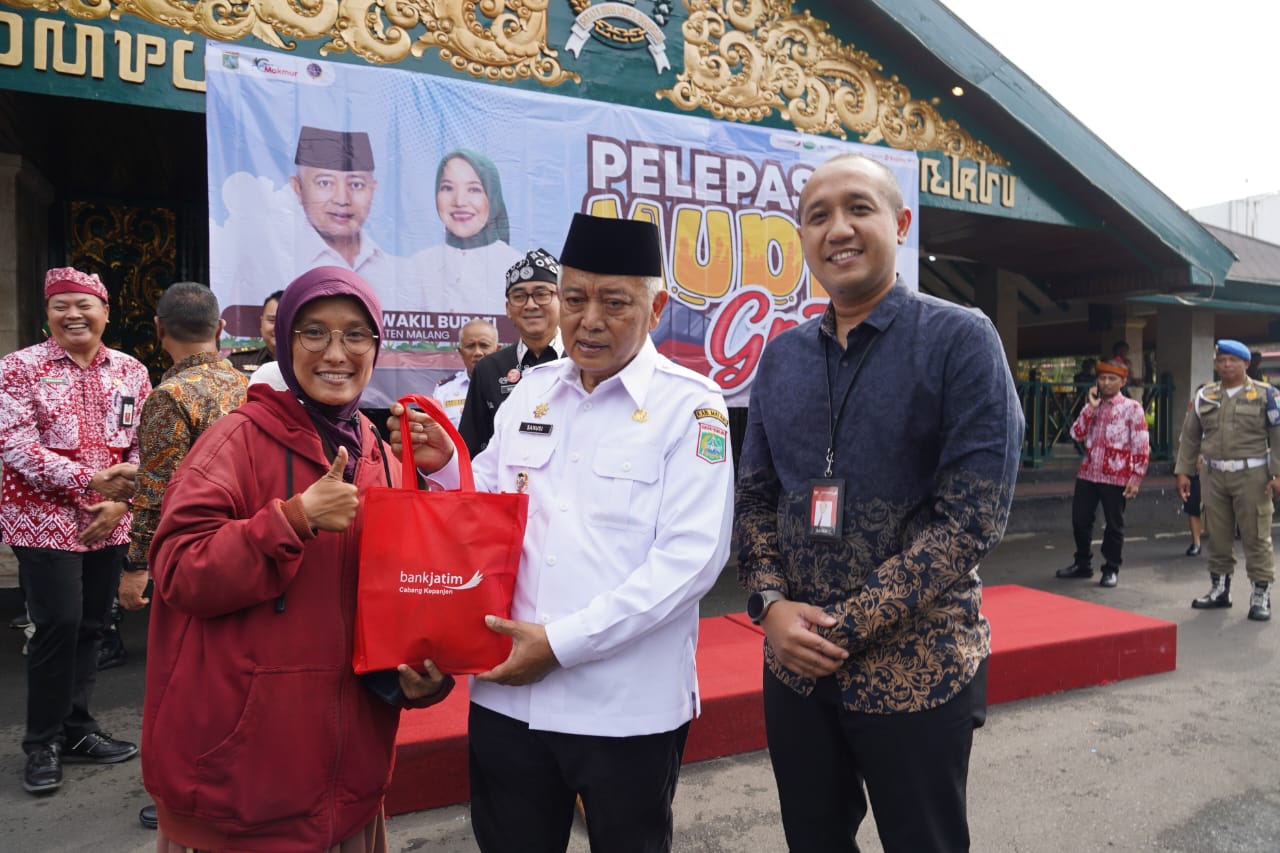 PEDULI: Bupati Malang Sanusi dan Pimpinan Bank Jatim Kepanjen, Satria Dananjaya (kanan) menyerahkan takjil kepada pemudik dalam Mudik Gratis Pemkab Malang, Kamis (27/3).
