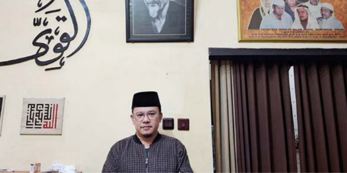 LANJUTKAN DAKWAH: KH Ahmad Fauzan Sholeh, cucu kelima dari KH Abdullah Arlidin berpose di depan foto KH Abdullah Arlidin di kediamannya di Kecamatan Pagak, Jum&rsquo;at lalu (28/3).
