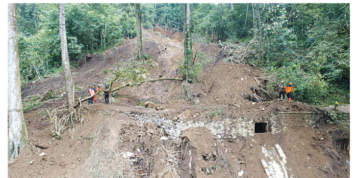 TERTIMBUN LONGSOR: Petugas BPBD provinsi Jatim meninjau kondisi Jalan Raya sumberbrantas-pacet yang masih tertim bun material longsor kemarin (6/4). (SARIYO NURSENO FOR RADAR MALANG)