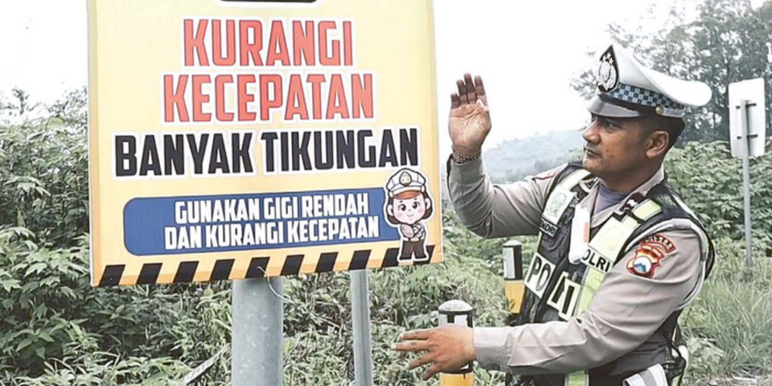 KURANGI KECEPATAN: Anggota Satlantas Polres Malang memperhatikan rambu imbauan setelah dipasang di jalur menuju wisata Bromo kemarin.