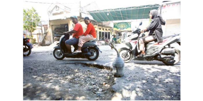 MEMBAHAYAKAN: Sebuah galon berisi tanaman dipasang warga di Jalan Tambakrejo sebagai peringatan kepada pengguna jalan karena ada lubang. (ANGGER BONDAN/JAWA POS)