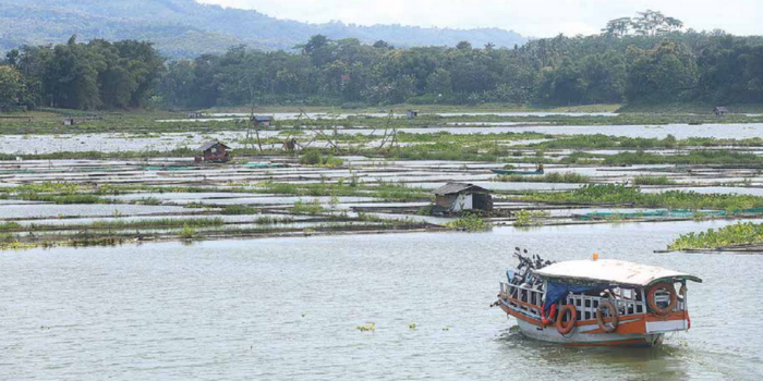 TUNGGU KEPASTIAN PROYEK PLTS: Perahu transportasi melintasi area Keramba Jaring Apung (KJA) di Bendungan Sutami, Sumberpucung (Darmono/Radar Malang).