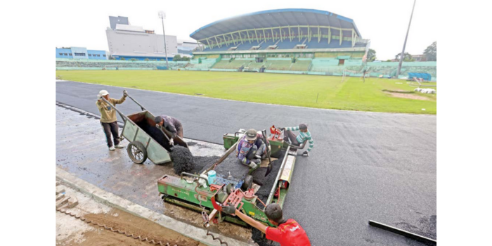 OPTIMISTIS TEPAT WAKTU: Para pekerja tengah memasang lapisan styrene butadiene rubber (SBR) untuk lintasan atletik di Stadion Gajayana, kemarin (24/4) (DARMONO / RADAR MALANG).