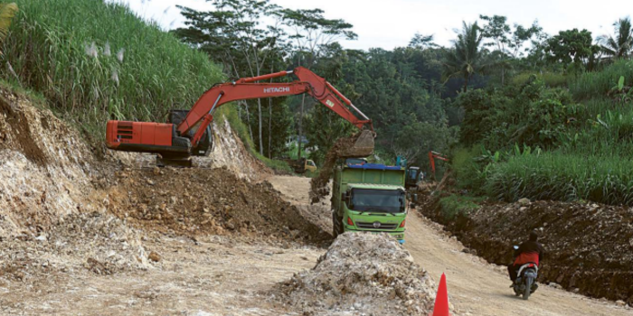 Satu unit alat berat diturunkan untuk meratakan ruas jalan yang miring di Desa Srigonco, Kecamatan Bantur kemarin (28/4) (Darmono/radar malang).