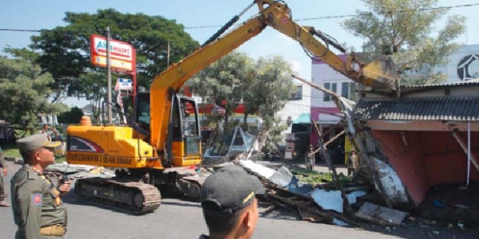 RATA: Petugas menggunakan alat berat untuk merobohkan bangunan liar di atas saluran air di Jalan Rajawali, Desa Gemurung, Kecamatan Gedangan, kemarin (29/4).