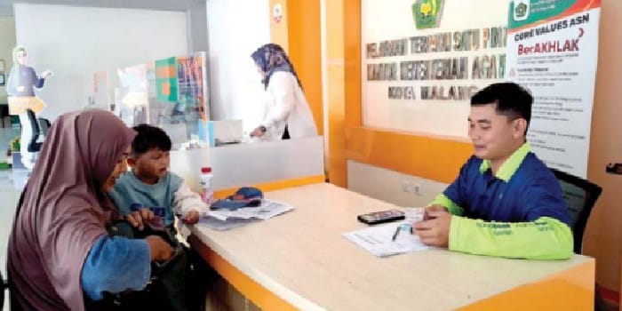 TUNGGU JADWAL BERANGKAT: Staf Kantor Kemenag Kota Malang melayani salah satu warga, beberapa waktu lalu. Kemenag menutup jadwal pelunasan Bipih pada 25 April lalu.