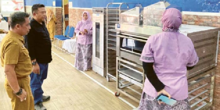 MENINJAU: Plt Kepala Disnaker Kabupaten Malang Yudhi Hindharto (kiri) melihat perlengkapan pembuatan bakery di sela pelatihan di Desa Tajinan, Kecamatan Tajinan pada 29 April lalu
