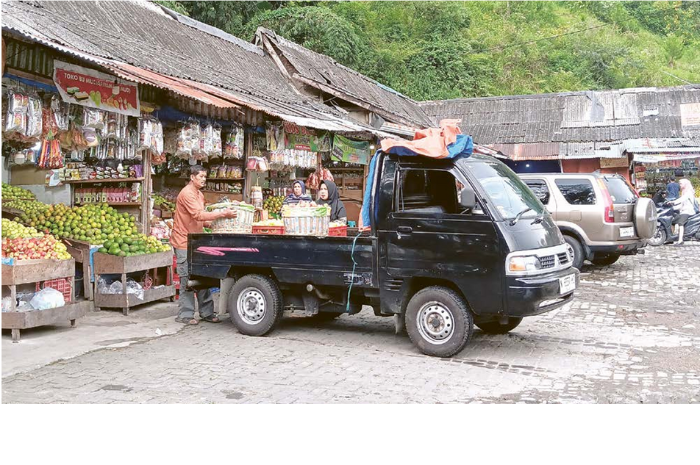 DIBANJIRI PEMBELI: Seorang pedagang di Pasar Wisata dewi Sri Pujon mengangkat buah dari pikap ke kios untuk dijual ke pembeli kemarin. (INDAH MEI YUNITA/RADAR KANJURUHAN)