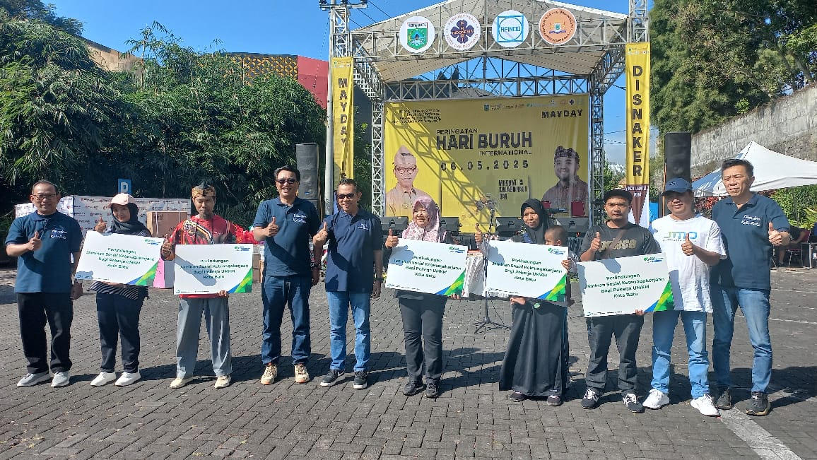 SERAHKAN BANTUAN: Wali Kota Batu Nurochman (lima dari kiri) didampingi Kadisnaker Thomas Wunang Tjahjo (kiri) menyerahkan bantuan premi BPJS Ketenagakerjaan kepada pelaku UMKM.
