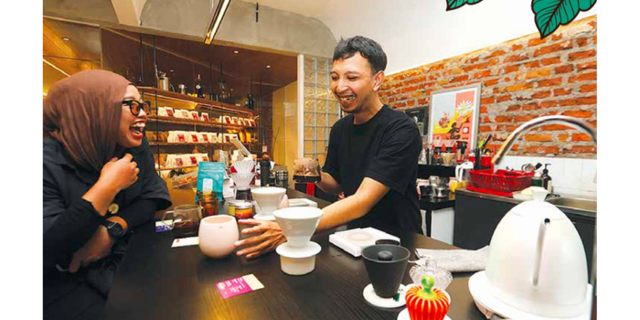 BAGIAN DARI LAYANAN: Hanif Zenid, Barista Motiv Coffee bercengkerama dengan salah satu pelanggan, Kamis lalu (15/5).