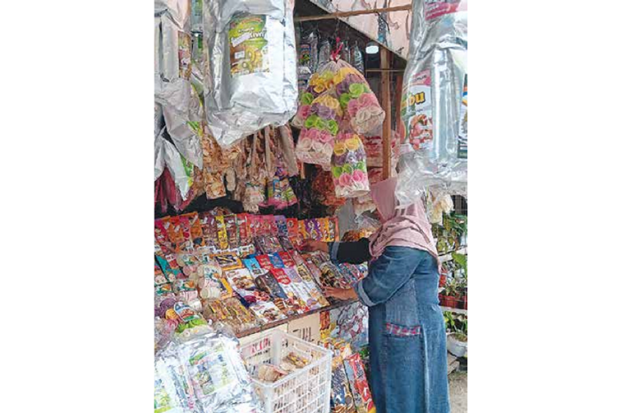 OMZET MEROSOT: Salah seorang wisatawan Kafe Sawah Pujon Kidul, Kecamatan Pujon mampir membeli keripik buah. (INDAH MEI YUNITA/RADAR KANJURUHAN)